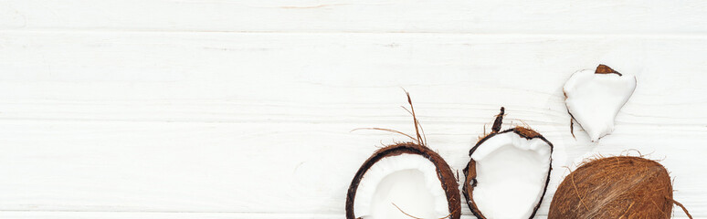 top view of coconut halves on white wooden surface, panoramic shot
