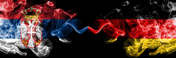 Serbia vs Germany, German smoky mystic flags placed side by side. Thick colored silky smokes combination of Serbian and Germany, German flag