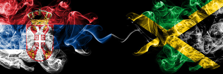 Serbia vs Jamaica, Jamaican smoky mystic flags placed side by side. Thick colored silky smokes combination of Serbian and Jamaica, Jamaican flag