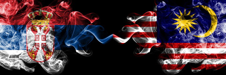 Serbia vs Malaysia, Malaysian smoky mystic flags placed side by side. Thick colored silky smokes combination of Serbian and Malaysia, Malaysian flag