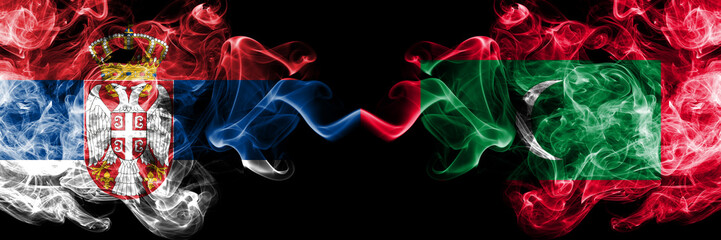 Serbia vs Maldives, Maldivian smoky mystic flags placed side by side. Thick colored silky smokes combination of Serbian and Maldives, Maldivian flag
