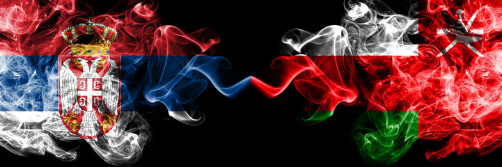 Serbia vs Oman, Omani smoky mystic flags placed side by side. Thick colored silky smokes combination of Serbian and Oman, Omani flag