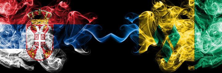 Serbia vs Saint Vincent and the Grenadines smoky mystic flags placed side by side. Thick colored silky smokes combination of Serbian and Saint Vincent and the Grenadines flag