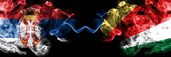 Serbia vs Seychelles, Seychelloise smoky mystic flags placed side by side. Thick colored silky smokes combination of Serbian and Seychelles, Seychelloise flag