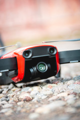A small red drone placed on the pebbles for the take off