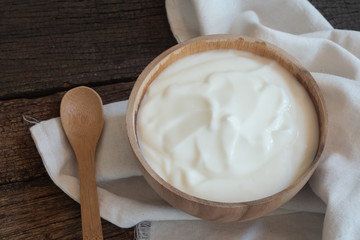 Fototapeta na wymiar Natural homemade plain organic yogurt in wood bowl on wood texture background