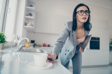 Portrait of beautiful stylish trendy pensive lady hold hand modern technology want mug beverage lean hurry late busy overworked dressed jacket blazers trousers pants apartment light
