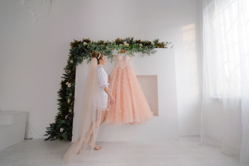 Bride in bathrobe admiring her wedding dress