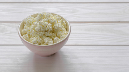 cottage cheese in a pink bowl on a light wooden table