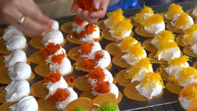 Delicious Thai street dessert, Kanom Buang, Thai Crispy Pancake or Thai Crepe, with varieties of fillings such as sweet white custard cream and golden sweet egg floss or salty minced shrimp on fry pan