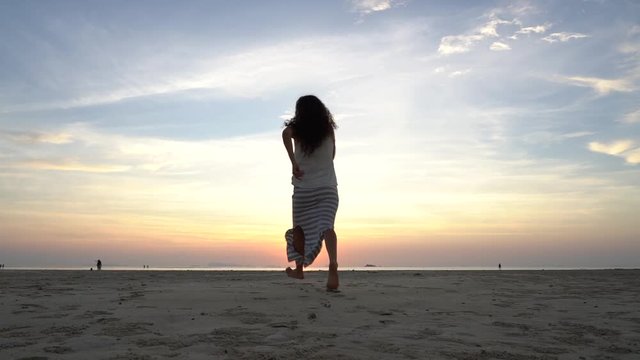 Young beauty girl dancing at tropical sand beach near sea water at paradise island at sunset. Summer concept. Holiday travel. Island Koh Phangan, Thailand