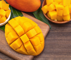 Fresh chopped mango cubes on wooden cutting board and rustic timber background. Tropical summer fruit concept, close up, macro, copy space.