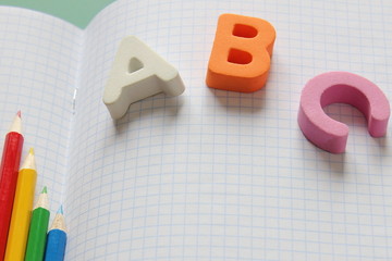 ABC-the first letters of the English alphabet and colored pencils on the school notebook.