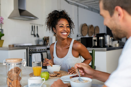 Happy woman enjoying breakfast with man at home