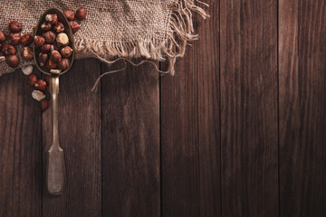 Hazelnuts on an old spoon and composition from old wood and material. Top view and empty space on right side for your text