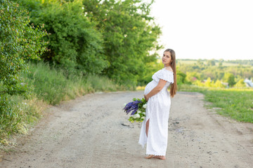 Pregnant girl with a bouquet in the hands of the city. Beautiful girl waiting for the baby