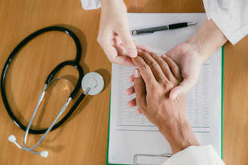 The female doctor hands the patient to comfort.Helping hands, care for the elderly concept