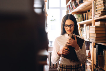 people, knowledge, education and school concept - happy student girl with book in library