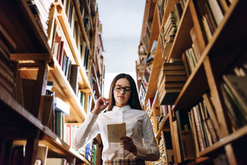 people, knowledge, education and school concept - happy student girl with book in library