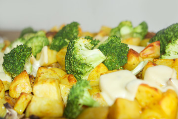 Baked potatoes with cheese, broccoli, mushrooms, turmeric and other spices from the oven close-up.