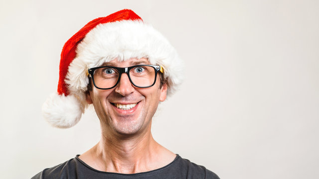 Young man in Christmas hat on grey background. Successful guy wearing santa hat. Christmas plan, holidays and sale concept