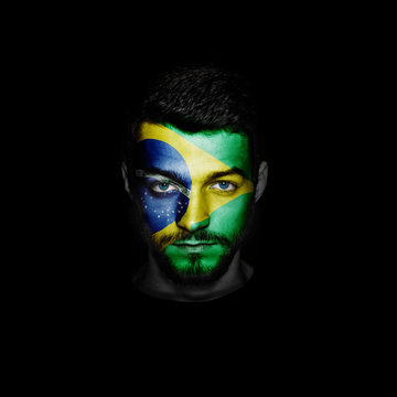 Flag of Brazil painted on a face of a man on black background.