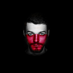 Flag of Poland painted on a face of a man on black background.