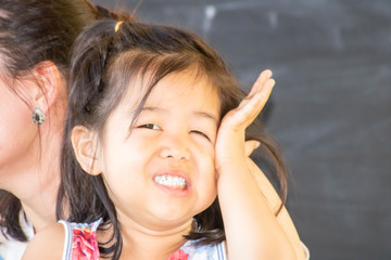 Petite fille eurasienne, chinoise et française, se grattant la joue après une attaque de moustique