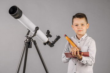 young astronomer looks through a telescope and writes in the tablet