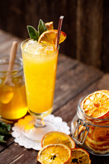 Glass cup of liquor cocktail, jar of honey and sliced oranges