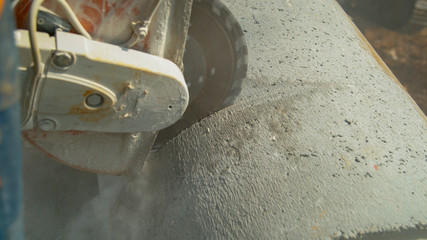 CLOSE UP: Angular saw grinding through a concrete tube at a construction site.