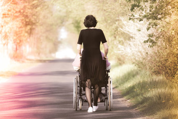 A woman pushing a wheelchair with a disabled person