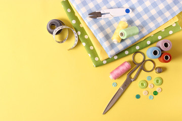 sewing accessories on a colored background top view.