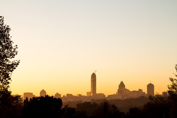 Naklejka premium Wschód słońca nad panoramą Sandton w Johannesburgu, RPA, Afryce. Sylwetka budynków Sandton. Plac Sandton i Nelson Mandela to popularne miejsca turystyczne.