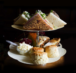 Afternoon tea food – sandwiches, scones, cake, carrot cake, apple pie, jam, clotted cream – on...