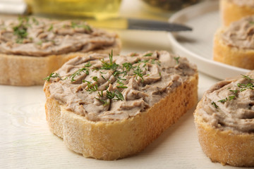 Fresh homemade chicken liver pate with herbs for bread on a white wooden table. A sandwich. close-up