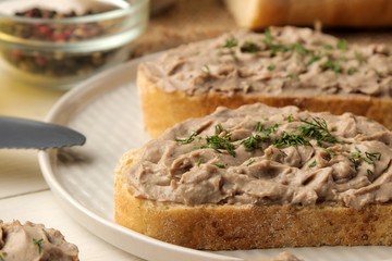 Fresh homemade chicken liver pate with herbs for bread on a white wooden table. A sandwich. close-up