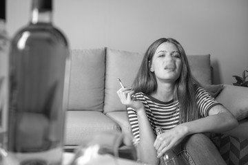 Young woman with addiction to alcohol and cigarettes relaxing at home