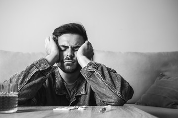 Young man with addiction to alcohol and drugs at home