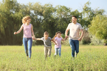 Obraz premium Happy family running in park on summer day