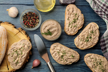 Fresh homemade chicken liver pate with herbs on bread on a blue wooden table. A sandwich. top view