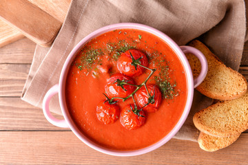 Pot of tasty tomato cream soup on wooden table