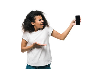 displeased african american girl gesturing while holding iphone with blank screen isolated on white