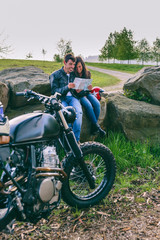 Fototapeta na wymiar Young couple sitting looking at a map during a motorcycle trip