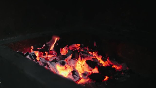 Beautiful red fire from slice wood, dark grey black coals inside metal brazier. Wood burning in the brazier on bright yellow fire. Flames fires preparation for cooking barbecue. Brazier bbq in 4k