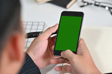 Cropped shot man using mockup mobile phone with green screen montage.