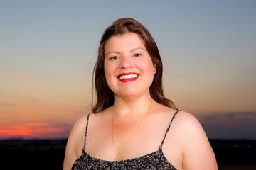 Closeup portrait of beautiful lady outdoors with sunset behind her.
