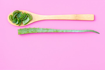 Medicinal plant aloe vera on a wooden spoon on a pink background