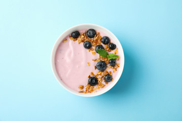 Yogurt with granola, blueberry and mint on color background