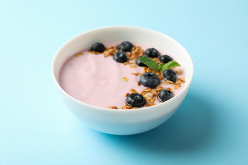 Yogurt with granola, blueberry and mint on color background